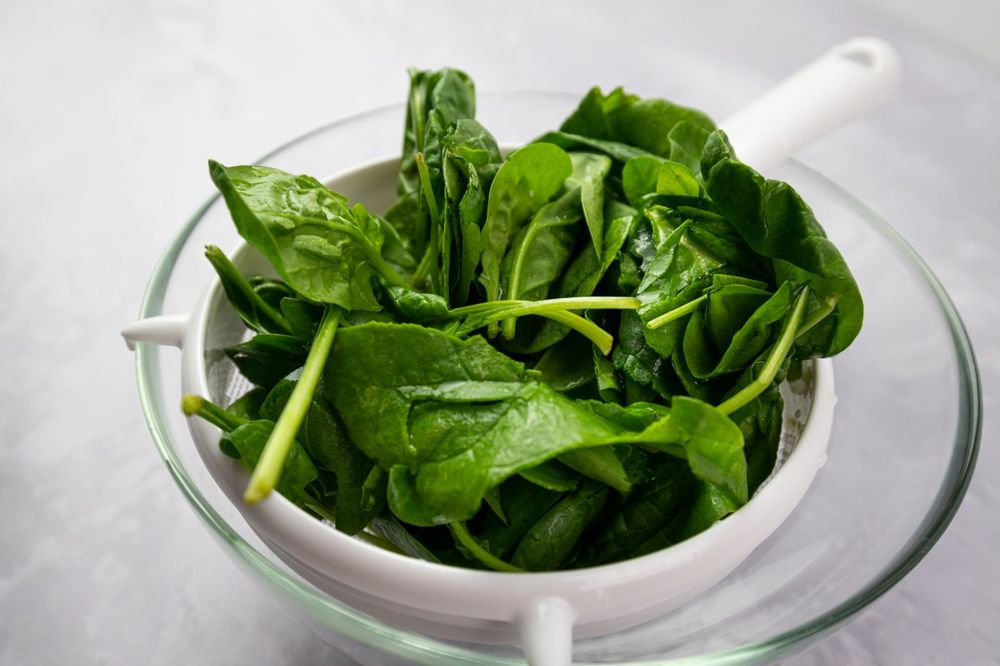 Fresh spinach leaves in a white colander
