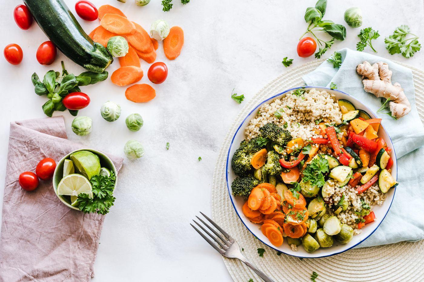 A colourful bowl of quinoa, leafy greens and roasted vegetables on a bright table