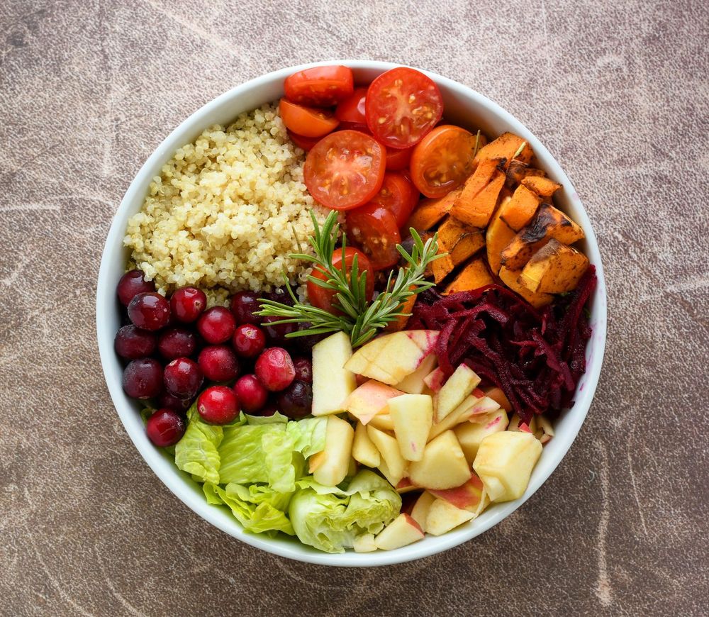 A nourishing bowl of quinoa, tomatoes, greens and fruit