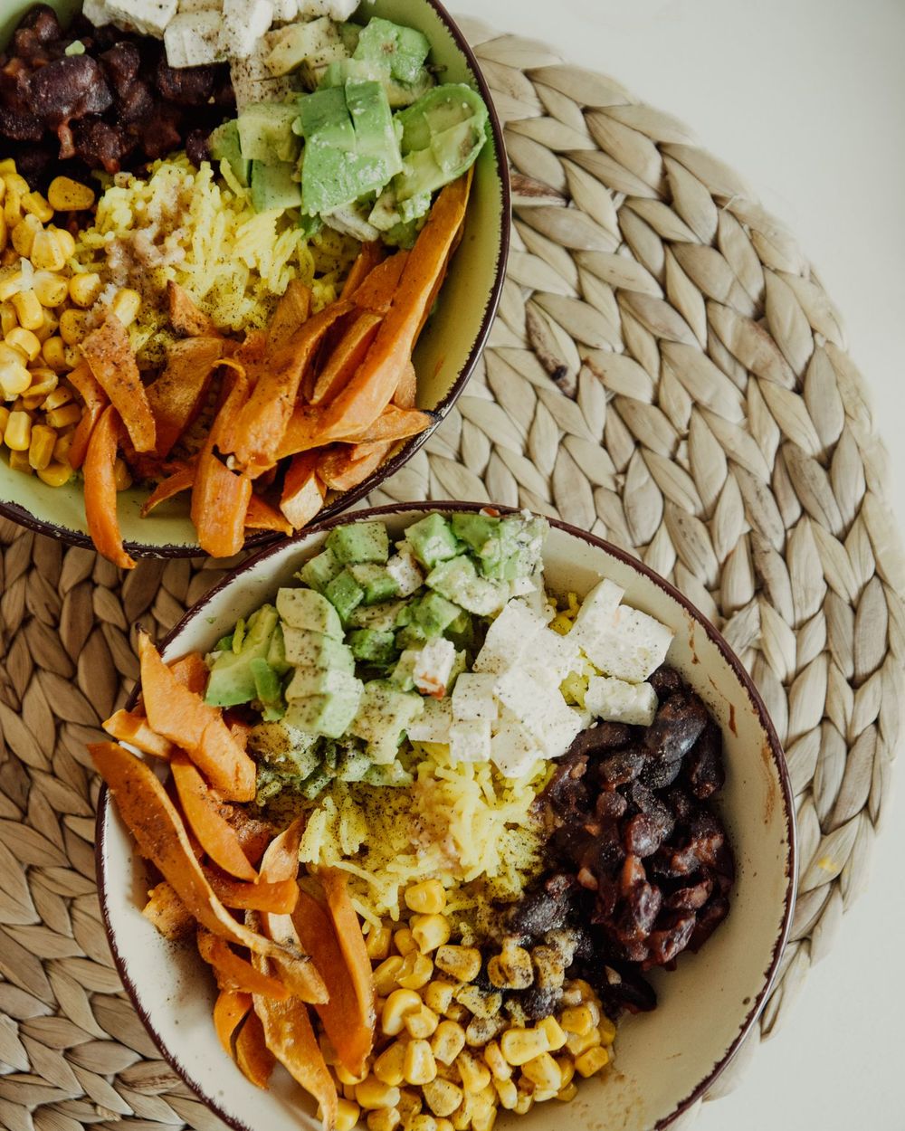 Two colourful vegetable bowls with avocado, corn and beans seen from above