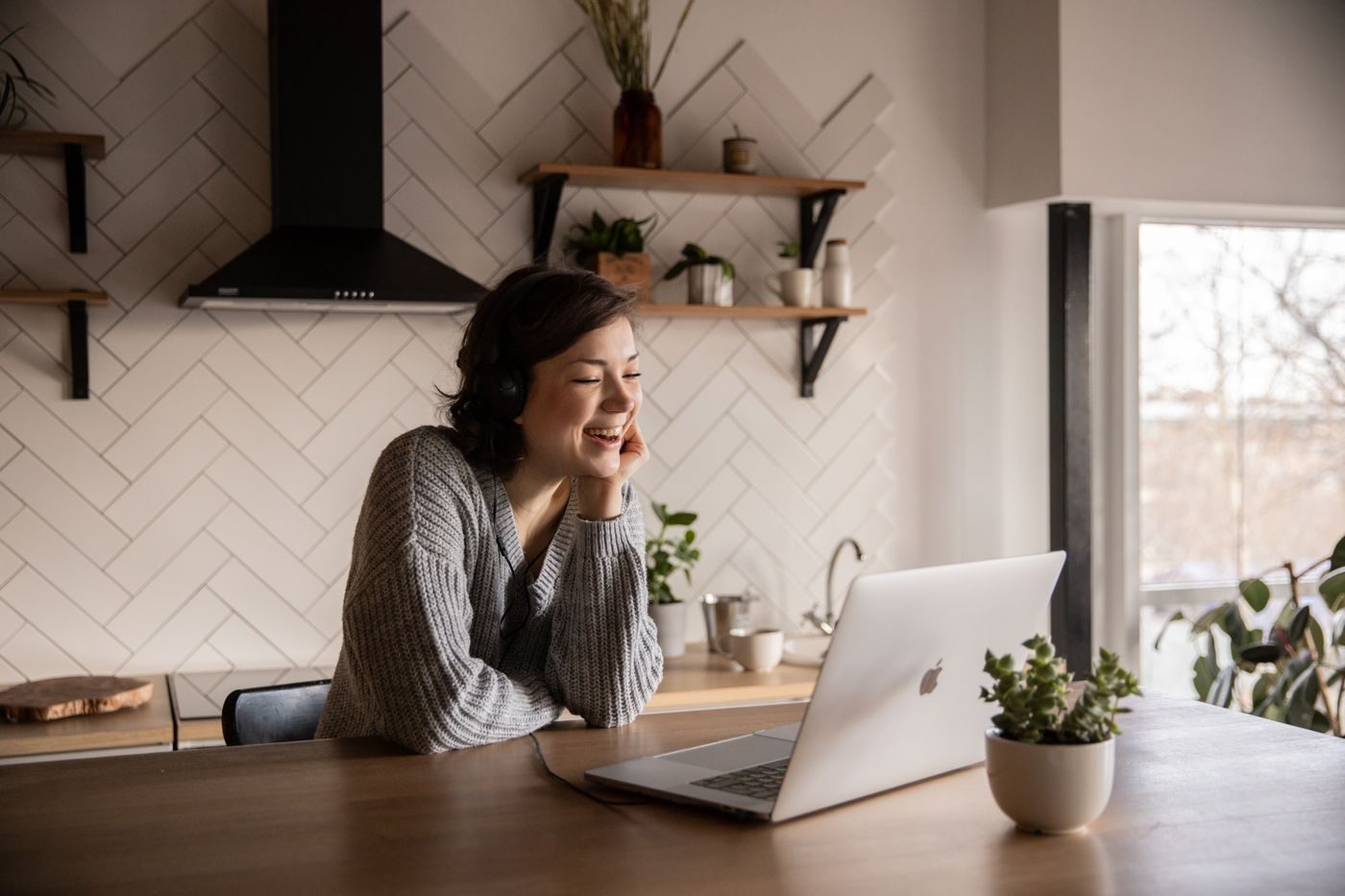 A smiling woman on a video call on her laptop at home